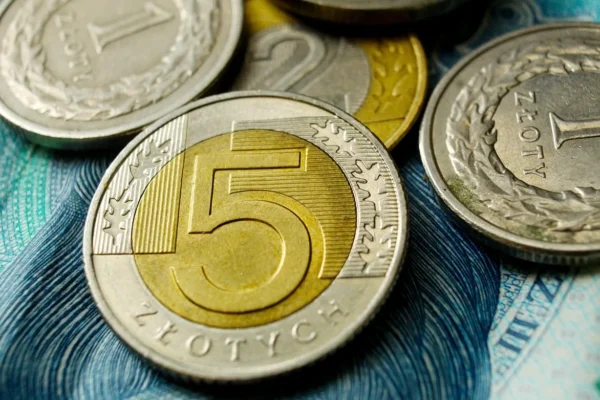 Kalkulator i banknoty 100 zł na biurku — porównanie konta oszczędnościowego i lokaty