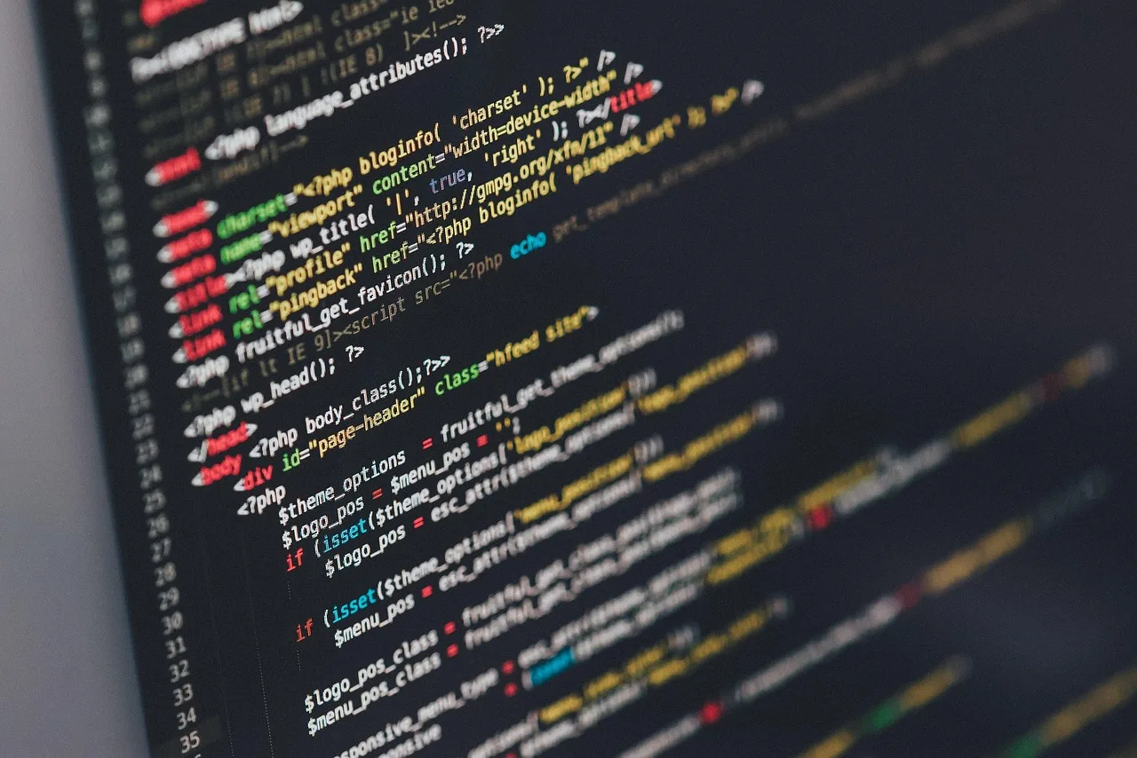 Programista pracuje przy laptopie z kodem na ekranie