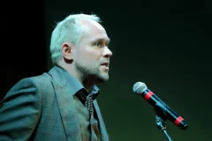 Prelegent na scenie konferencyjnej z mikrofonem przed publicznością — prezentacje publiczne jako umiejętność techniczna